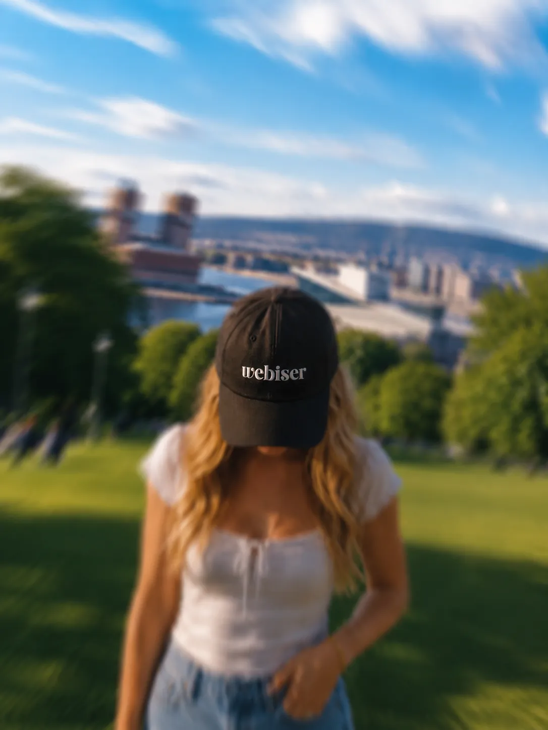 Kvinne med Webiser-caps i en park med utsikt over byen